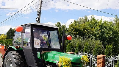 Traktor i uśmichnięty kierowca, machający.