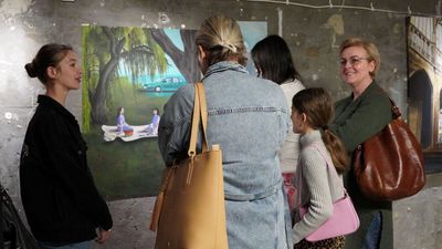 Grupa kobiet rozmawiająca o obrazie na który spoglądają