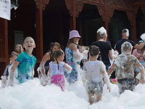 Dzieci pokryte białą pianą bawiące się i biegające podczas plenerowego przyjęcia zwanego "piana party"