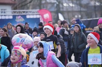 Dzieciaki podczas rozgrzewki do II Słodkiego Biegu. Wyróżnia się wysoki chłopak w czapce Świętego Mikołaja
