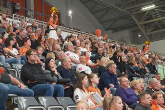 Zbliżenie na widownię z kibicami. Pomiędzy wejściem na sektory cheerlederki dopinguja zawodników