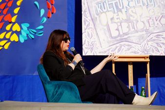 Anna Gacek na scenie muszli koncertowej siedzi na fotelu i mówi do mikrofonu