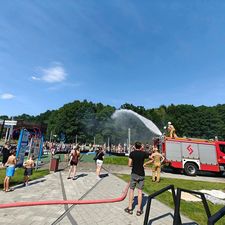 Wóz strażacki polewa ludzi w upalny dzień na Ośrodku Wypoczynku Niedzielnego