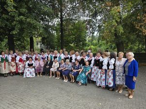 Wszyscy goście i członkinie KGW stoją na zewnątrz na tle drzew pozując do grupowego zdjęcia