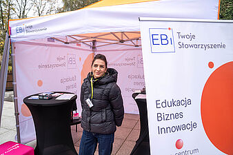 Kobieta stoi pod namiotem stowarzyszenia EBI