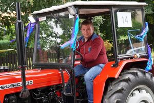 mężczyzna w ciągniku w dożynkowym korowodzie