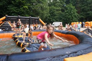 Dziewczynka pokonująca dmuchany tor przeszkód nad wodą