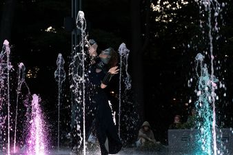 Kobieta podnosząca dłonie nad fontannami