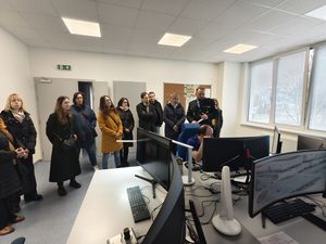 goście spotkania w biurze patrzą na monitor komputera przed którym siedzi pracownik