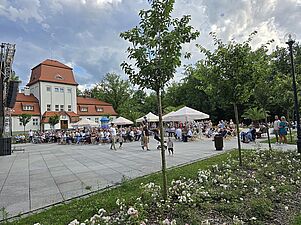 Widok na plac przed sceną - roślinność i publicznośc w dalszej perspektywie