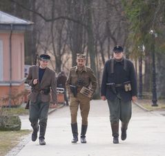 Mężczyźni w strojach wojskowych z lat wojennych, na ramionach mają przewieszoną broń