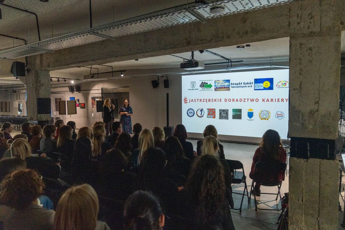 goście siedza przed plansza podczas konferencji