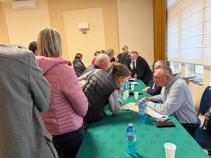 ludzie przed stołem prezydialnym zadają pytania