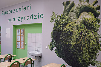 Ściana z grafiką zielonego serca i napisem Zakorzenieni w przyrodzie
