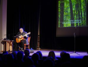 Artysta podczas śpiewu, za nim napis Wyklęci niezłomni