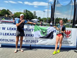 Aneta i Wojtek pozują z rozciągniętą flagą miasta