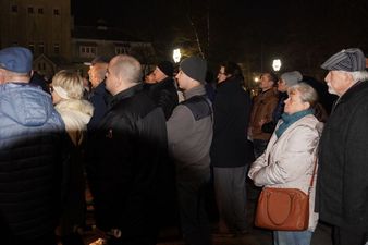 Grupa dorosłych uczestników w zimowych kurtkach stojących nocą w parku i patrzących w jednym kierunku