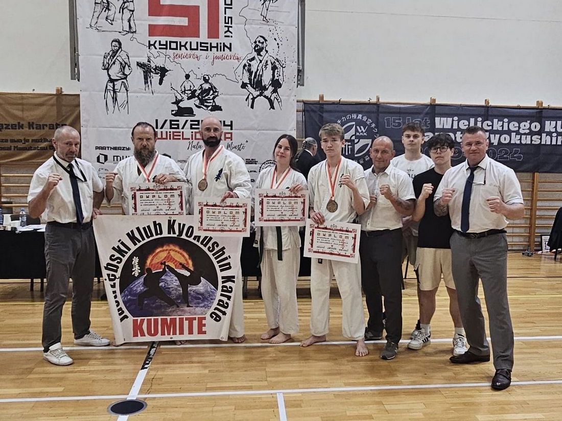 Cała drużyna pozuje do zdjęcia z medalami, dyplomami i klubowym banerem