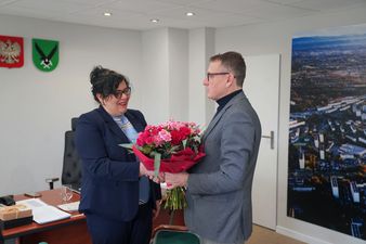 Prezydent Michał Urgoł wręcza Marii Jasionek bukiet czerwono-różowych kwiatów