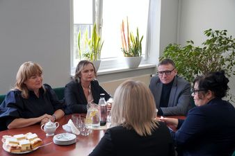 przy stole Ewa Gutowska, Barbara Więckowska, Michał urgoł, tyłem Maria Jasionek i Marzena Kuta w tle okno z kwiatkami doniczkowymi
