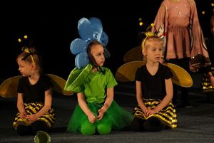 dzieci przebrane za kwiaty siedzą na scenie