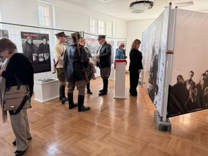 Wystawa na temat żołnierzy wyklętych, przed tablicami zwiedzający oglądają zdjęcia, na środku sali mężczyźni w strojach partyzantów z zabytkową bronią na ramionach