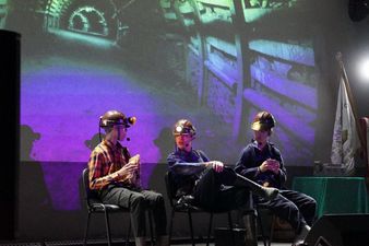 Kabaret - trzech młodych górników w strojach roboczych rozmawia pod ziemią podczas jedzenia