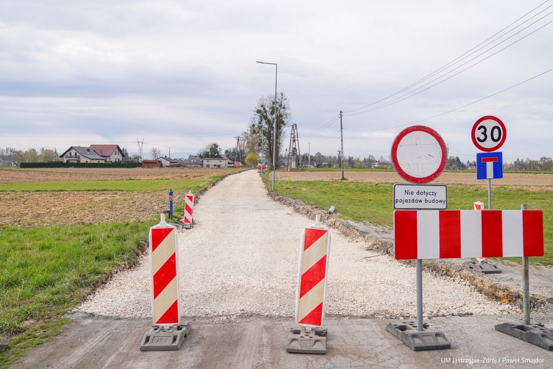 Widok na remontowaną ulicę długosza na pierwszym planie barierka i znak zakaz wjazdu w tle pola i budynki