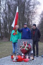 Organizatorzy uroczystości z polską flagą stojący wokół pomnika poświęconego żołnierzom wyklętym