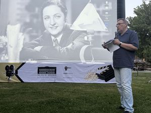 Dyrektor Muzeum Miejskiego Jędrzej Lipski stoi przy ekranie i mówi do mikrofonu