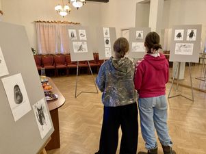 Dwie kobiety oglądające pracy znajdujące się na sztalugach.