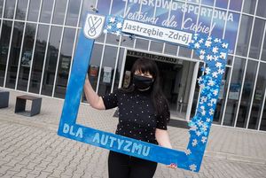 Pracownica MOSiR trzyma drewnianą, niebieską ramkę z napisem "dla autyzmu"