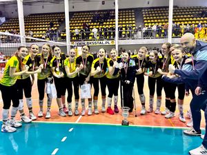 Cieszące się w półkole dziewczyny z zaciśnietymi prawymi pięściami z trenerami