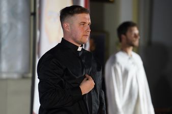 Mężczyzna ubrany na biały uosobiający Jezusa Chrystusa, na pierwszym planie mężczyzna ubrany w sutannę utożsamiający księdza Jana Machy