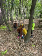 Kobieta z dziećmi schyla się by podniesć śmieci