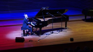 Zdjęcie przedstawia Adama Snopka grającego na fortepianie.