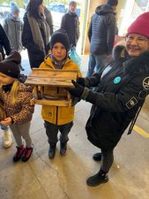 Grupa osób w wejściu, na pierwszy planie chłopiec trzymający karmik