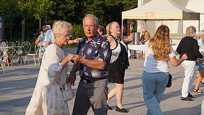 Mężczyzna i kobieta na parkiecie, trzymający się za ręce.