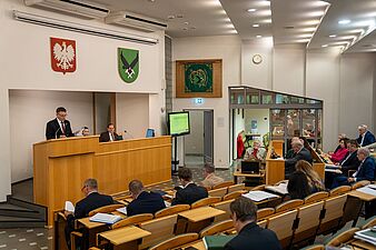Radni na sali sesyjnej, przemawia Prezydent miasta Michał Urgoł