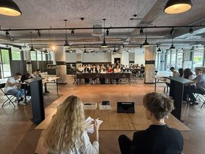 uczestnicy debaty siedzą przy stołach