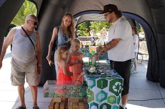 Stanowisko do eksperymentów fizycznych umieszczone pod namiotem, wokół dwie małe dziewczynki oraz dwoje dorosłych