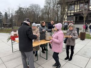 Dwie kobiety i mężczyzna stoją przy stoliku gdzie prezydent Michał Urgoł nalewa żurek