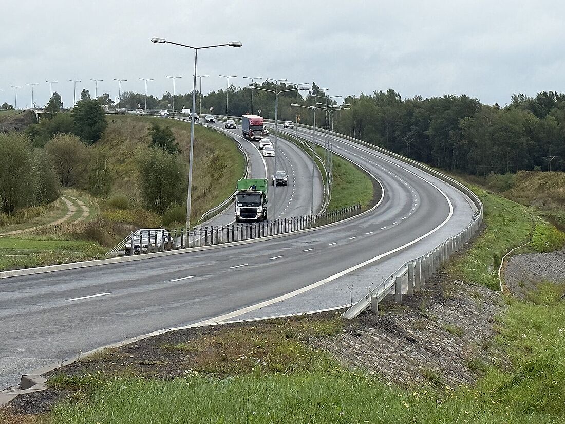 Widok z góry na wielopasmową drogę biegnącą po łuku z jadącymi ciężarówkami i samochodami osobowymi