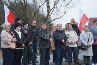 Tłum ludności zebrani na uroczystości upamiętniającej żołnierzy wyklętych, mężczyźni trzymają polskie flagi