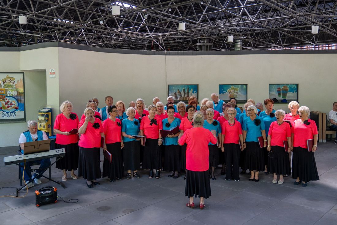 chór Melodia w czerwonych bluzkach i czarnych spódnicach podczas spotkania seniorów