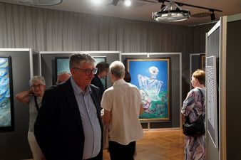Drugi zastępca prezydenta miasta Andrzej Matusiak patrzy na obraz w tle ludzie oglądający wystawę