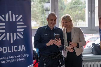 Przedstawiciel policji, obok stojąca kobieta.