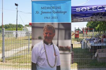 Plansza z informacją o memoriale ks. Janusza Rudzkiego z wizerunkiem