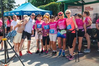 kobiety w różowych koszulkach i mezczyzna w jasnej koszulce pozują do zdjęcia