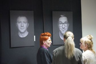 Trzy kobiety przed zdjęciami portetowymi mężczyzn